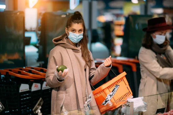 Молодая женщина в защитной маске делает покупки — стоковое фото