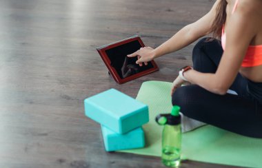 Yoga yapan genç bir kadın internetteki öğretmenle meşgul..
