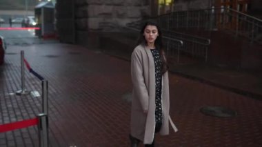 Gri montlu güzel kız sokakta yürüyor.