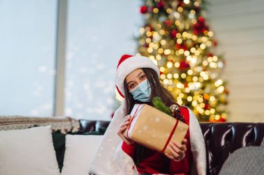 Noel arifesinde elinde Noel hediyesi tutan bir kız..