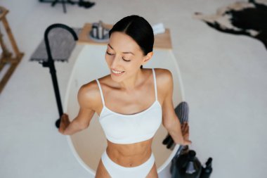 İç çamaşırlı çekici bir kadın banyonun yanında poz veriyor.