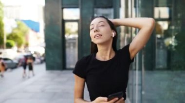 Yürürken kulaklıklı esmer bir kadının portresi.