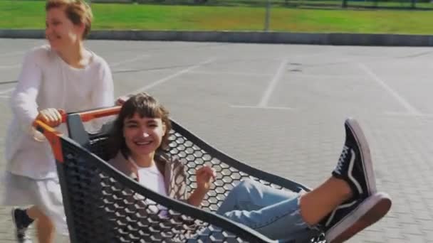 Girlfriends ride in a cart at the supermarket on the streets of the city. — Stock Video