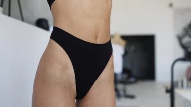 Güzel genç kız iç çamaşırlarıyla oturma odasında poz veriyor.