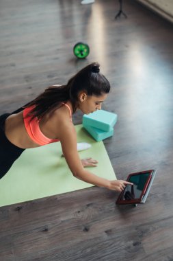 Yoga yapan genç bir kadın internetteki öğretmenle meşgul..