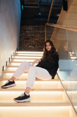 Genç ve güzel esmer manken merdivenlerde poz veriyor..