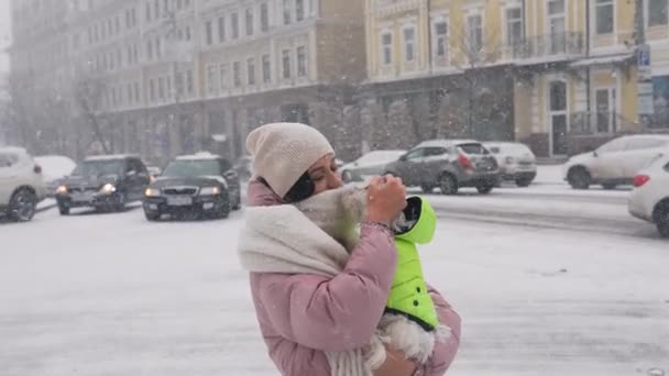 Kollarında köpek olan bir kız, kar yağıyor. — Stok video