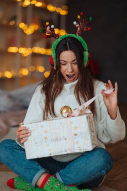 Kameraya gülümseyen yetenekli bir kız. Noel boynuzu takıyor..