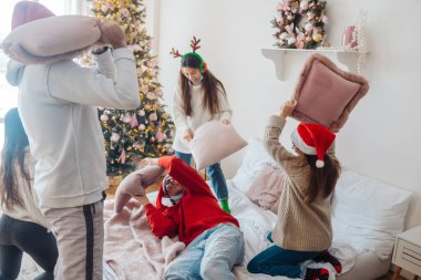 Çok ırklı arkadaşlar yeni yıl arifesinde yastıklarda kavga ederken eğlenirler.