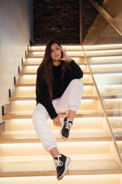 Genç ve güzel esmer manken merdivenlerde poz veriyor..