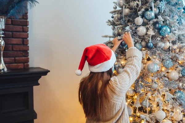 En ung kvinne pynter juletreet med medisinske masker. – stockfoto