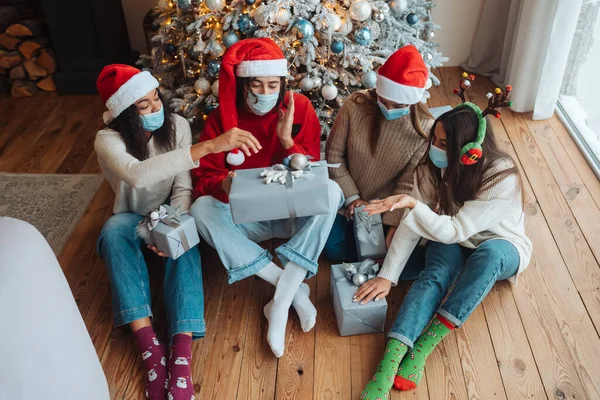 Багатоетнічна група друзів у Санта-капелюхах з подарунками в руках . — стокове фото