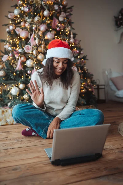 Kobieta w kapeluszu Mikołaja podczas rozmowy z przyjacielem online na laptopie — Zdjęcie stockowe
