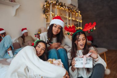 Noel Baba şapkalı, elinde hediyeler olan çok ırklı bir arkadaş grubu..