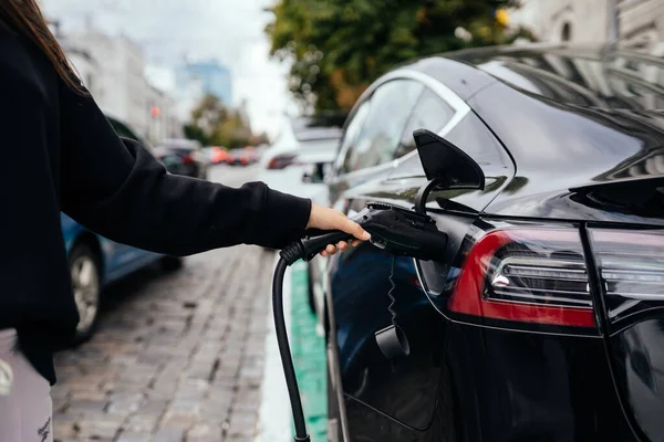 Kobieta w pobliżu elektrycznego samochodu. Pojazd naładowany na stacji ładowania. — Zdjęcie stockowe