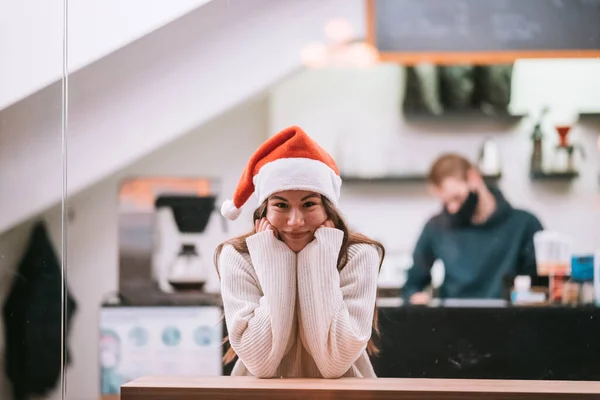 Gadis memakai topi Santa Claus duduk di kedai kopi — Stok Foto