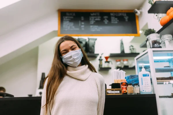 Девушка в защитной маске сидит в кофейне — стоковое фото