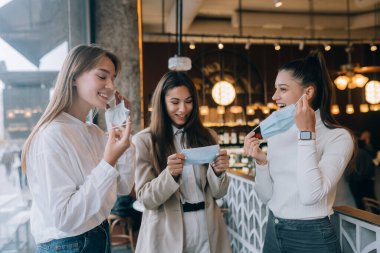 Kafkasyalı kadınlar bir kafede tıbbi maske takıyor.