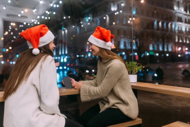 Kafede akıllı telefon kullanan iki genç kız..