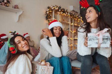 Noel Baba şapkalı, elinde hediyeler olan çok ırklı bir arkadaş grubu..