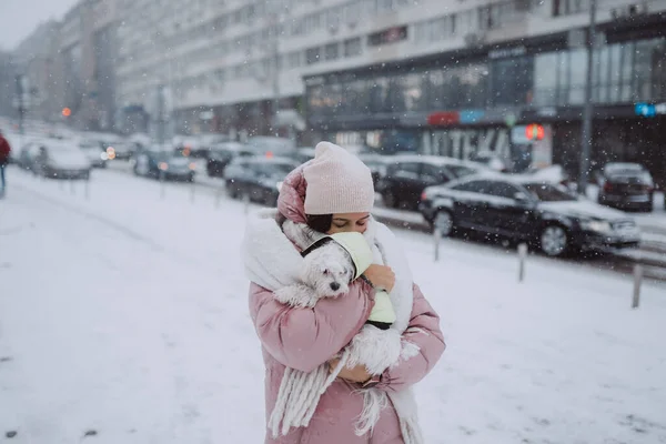 Menina com um cão em seus braços, neve está caindo — Fotografia de Stock