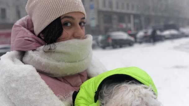 Flicka med en hund i famnen, snön faller — Stockvideo