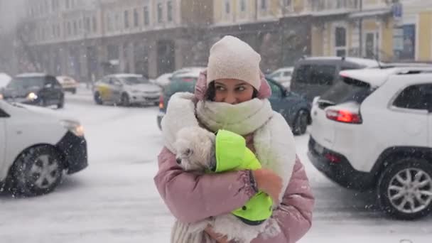 Flicka med en hund i famnen, snön faller — Stockvideo