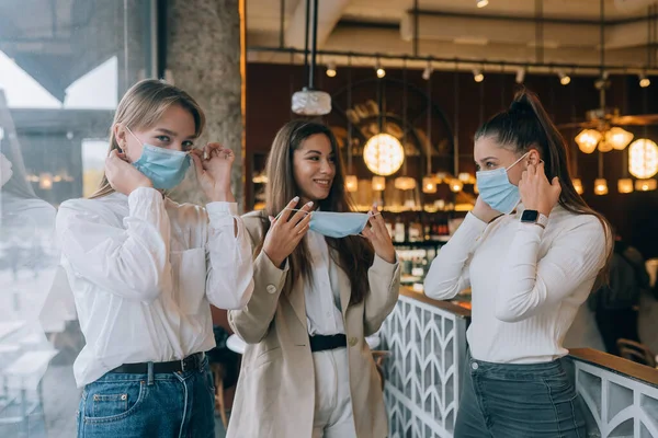 Кавказские женщины снимают медицинскую маску в кафе — стоковое фото