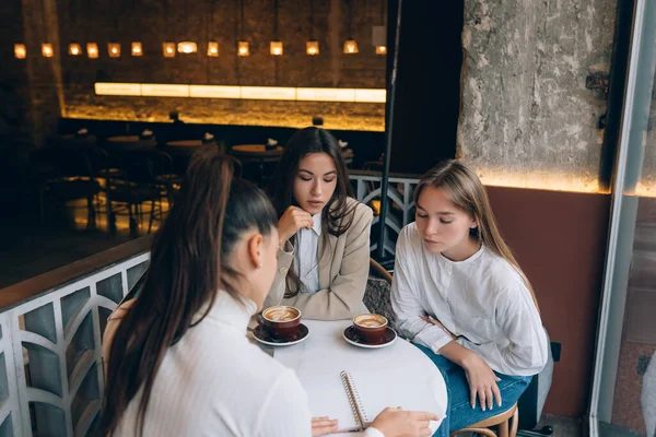 Um grupo de mulheres amigas em um café trabalhando em um projeto — Fotografia de Stock