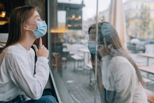 Dos mujeres con máscaras protectoras una frente a la otra, ventana entre ellas. —  Fotos de Stock