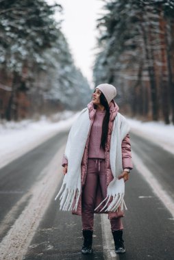 Karlı ormanda bir yolda beyaz bir kadının portresi.