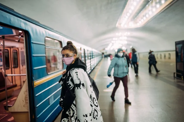 Νεαρή γυναίκα στέκεται στο σταθμό με ιατρική προστατευτική μάσκα — Φωτογραφία Αρχείου
