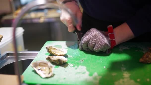 Las manos del cocinero abriendo una ostra. Vista cercana — Vídeo de stock