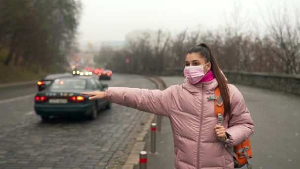 Jonge vrouw staat op de weg buiten het verhogen van de hand opzij vangen taxi — Stockvideo