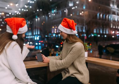 Kafede akıllı telefon kullanan iki genç kız..