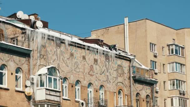 Человек убирает лед на крыше зданий. — стоковое видео