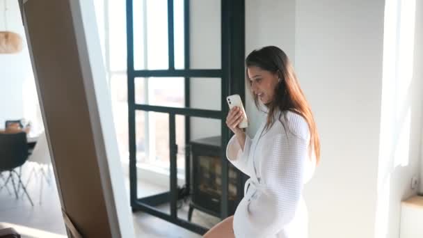 Young woman near a mirror in bathrobe. — Stock Video