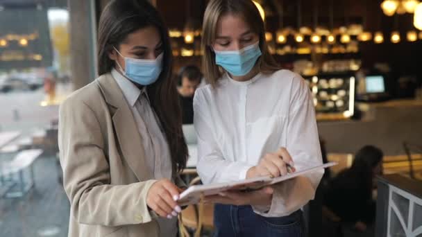 Twee zakenvrouwen met gezichtsmaskers die van mening verschillen over werk — Stockvideo