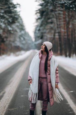 Karlı ormanda bir yolda beyaz bir kadının portresi.