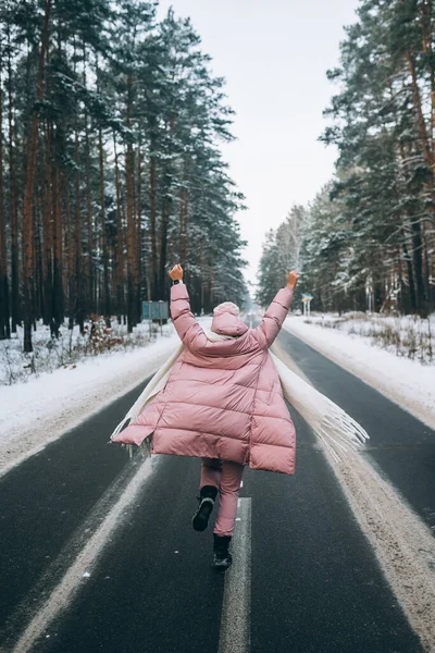 Portrait of a beautiful caucasian woman on a road through snowy forest — Stock Photo, Image