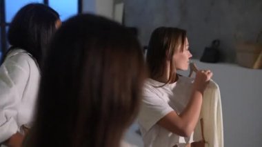 Pijamalı çekici genç kadınlar odadaki kıyafetleri seçiyor.