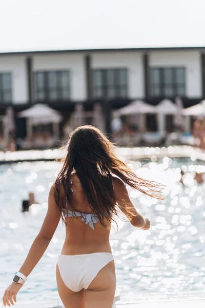 身穿白色泳衣的年轻女子站在游泳池的后面. — 图库照片