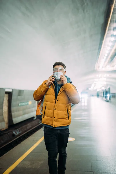 Парень, стоящий на станции в медицинской защитной маске на лице. — стоковое фото