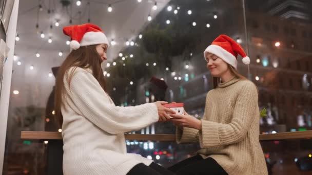 Flickan ger en gåva till sin kvinnliga vän på kafé — Stockvideo