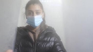 Koruyucu maskeli bir kız dezenfeksiyon odasından çıkıyor.