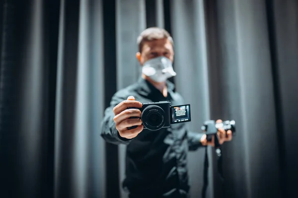 Retrato de cerca de un tipo sosteniendo en las manos la cámara con máscara de seguridad —  Fotos de Stock