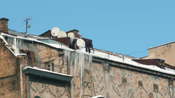 Uomo che rimuove il ghiaccio sul tetto degli edifici. — Video Stock