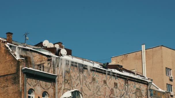 Человек убирает лед на крыше зданий. — стоковое видео