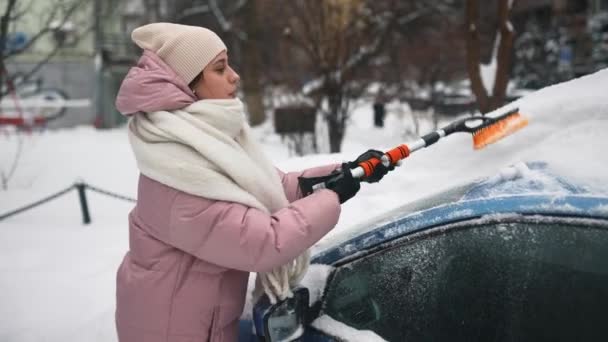 Женщина убирает снег из машины — стоковое видео