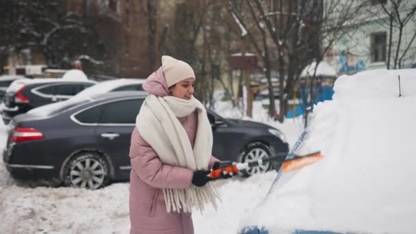 Женщина убирает снег из машины — стоковое видео